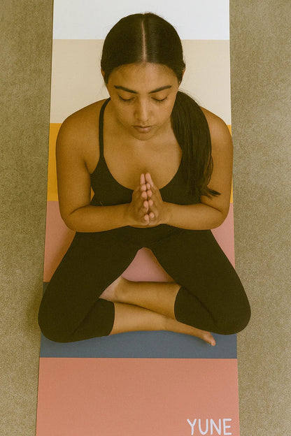 Woman practicing yoga on a Yune branded mat
