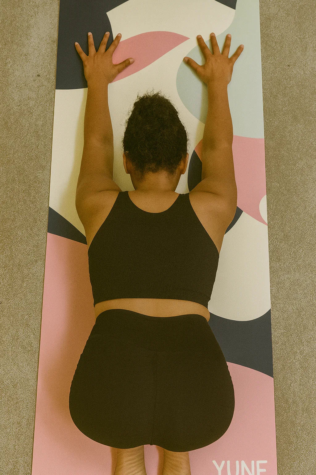 Person practicing yoga on a colorful mat with 'Yume' branding.