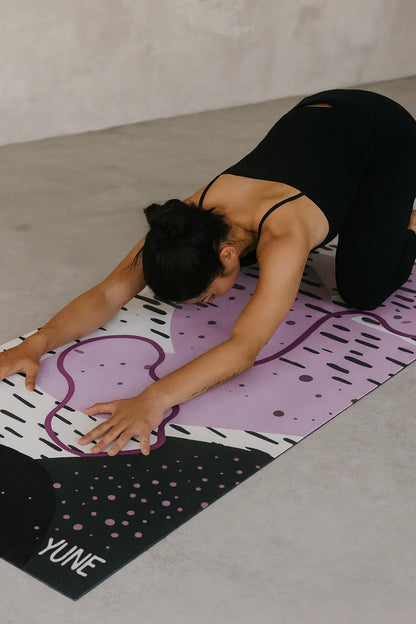 Person stretching on a colorful yoga mat with 'YUME' branding.