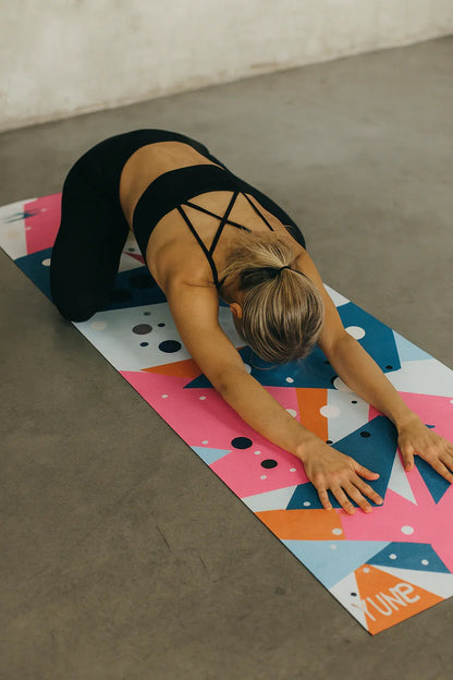 Person stretching on a colorful yoga mat in a home setting